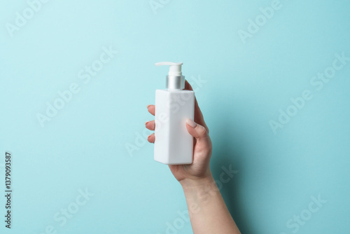 Obraz na płótnie Cosmetic bottle in woman hand on blue background. w salonie