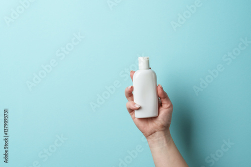 Obraz na płótnie Cosmetic bottle in woman hand on blue background. w salonie