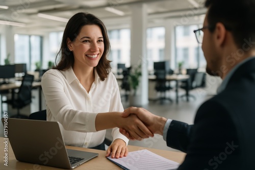 Smiling Businesswoman in White Shirt Shaking Hands with Colleague During Job Interview or Business Agreement in Modern Office
