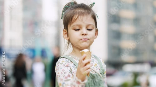 girl child eats ice cream in park and has fun.