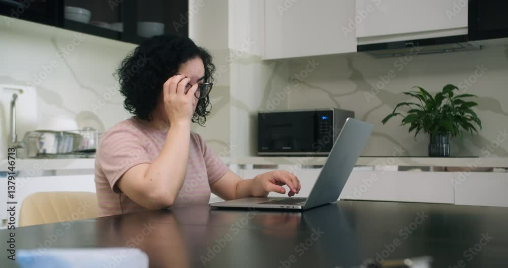Tired overworked lady feeling eye strain after using computer working from home. Headache, visual fatigue and eyestrain concept. Exhausted young woman taking off glasses massaging dry irritable eyes.