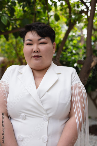 Woman in white dress poses confidently in garden setting at a modern venue
