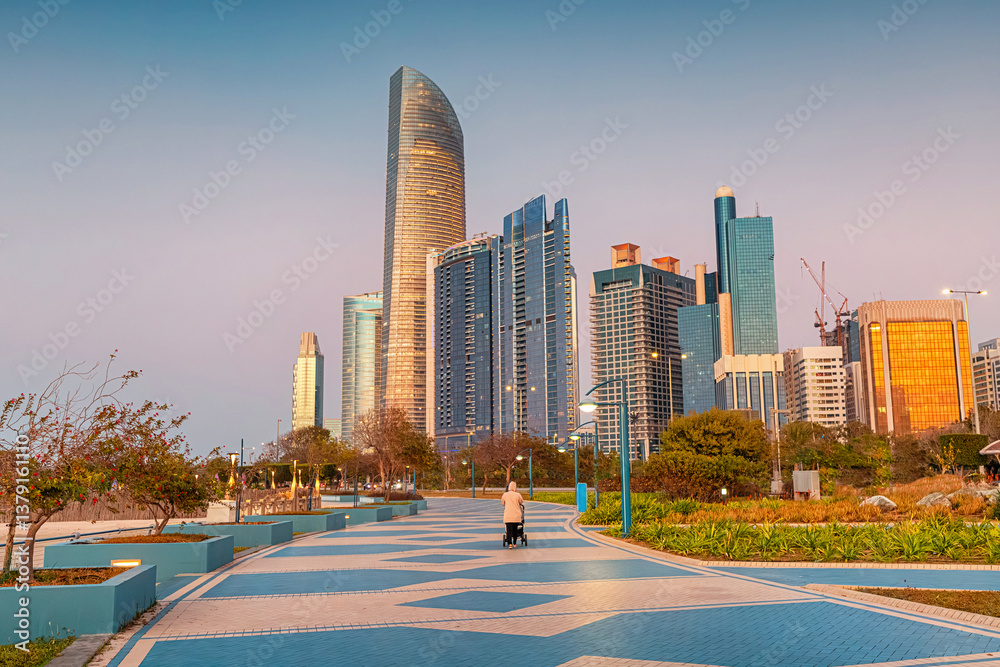 Modern skyscrapers rising above a promenade in Abu Dhabi at sunset