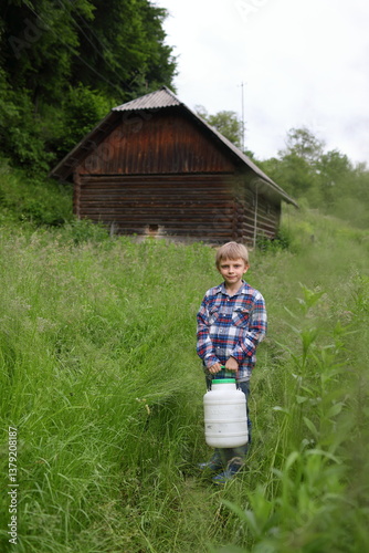 A boy in a village carries a can of milk