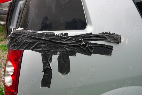 Obraz na płótnie A gray car's rear panel is covered in black tape to hold it together. w salonie