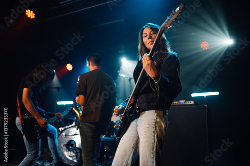 Female musician playing bass guitar during live rock concert photo