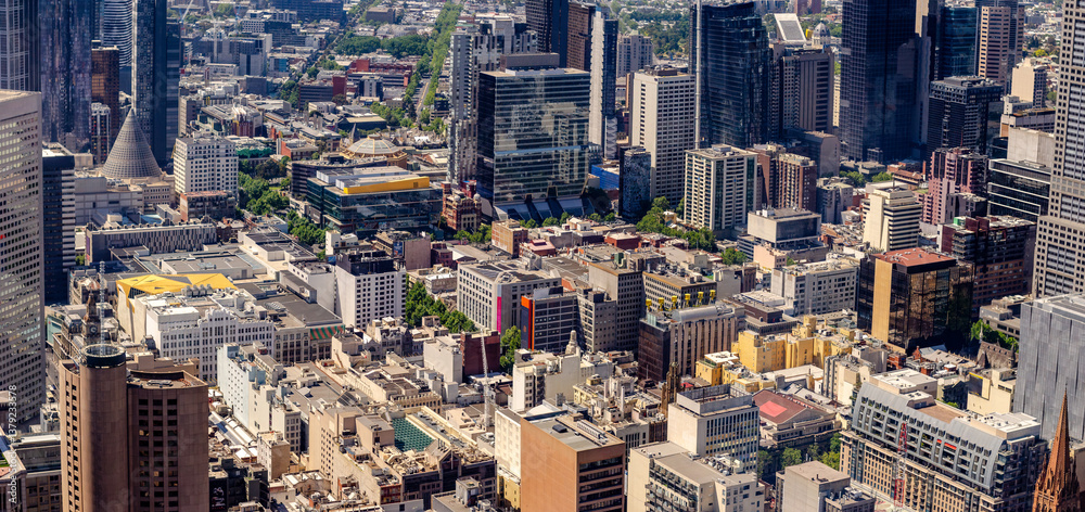 Naklejka premium Panoramic aerial view of Melbourne, Australia, with a mix of gleaming skyscrapers and mid-rise buildings spread across the bustling CBD. Well-organized grid pattern of urban streets from above.