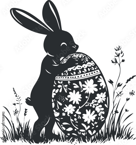 Silhouette of a bunny holding a decorative Easter egg with floral patterns in grass.
