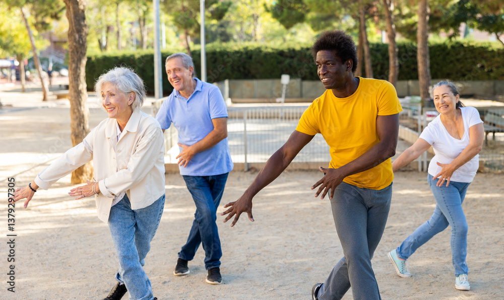 Positive mature women and men practicing vigorous dance movements in a summer park Positive mature women and men practicing vigorous dance movements in a summer park