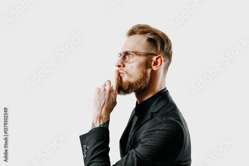 Obraz na plátně Side view of thoughtful young man in black suit with finger on lips