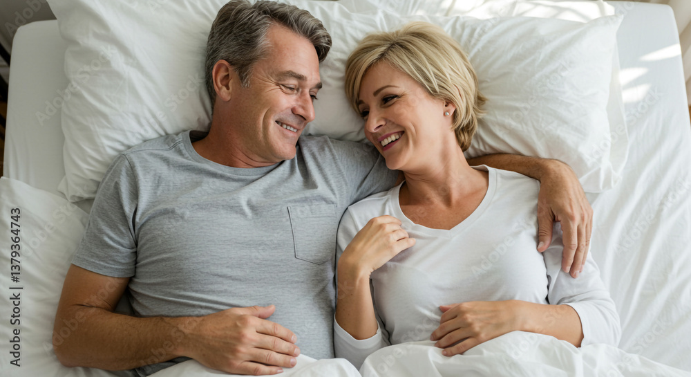 A mature couple's tender morning embrace in bed, sharing a quiet moment of intimacy and connection, soft natural light illuminating their happy faces. A mature couple's tender morning embrace in bed, sharing a quiet moment of intimacy and connection, soft natural light illuminating their happy faces.