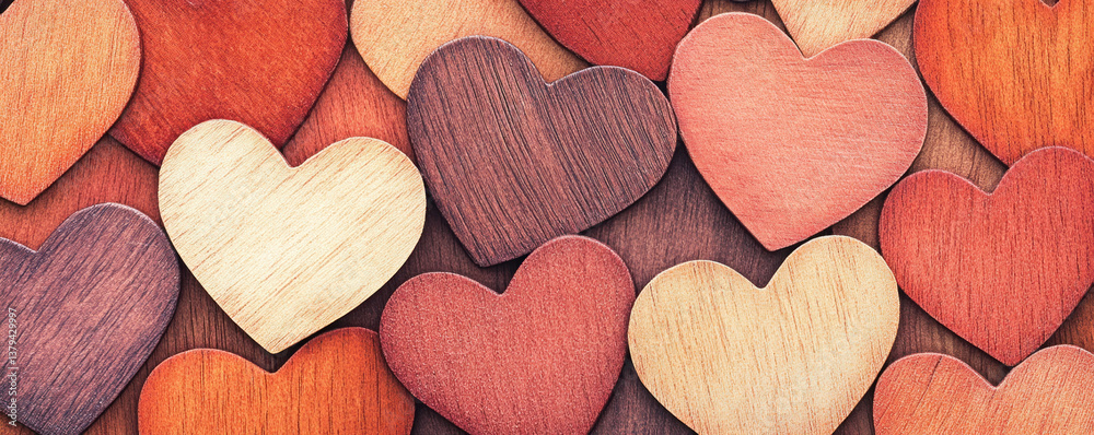 Obraz premium A bunch of wooden hearts are arranged in a pattern. The hearts are of different colors and sizes, and they are all placed on top of a wooden surface