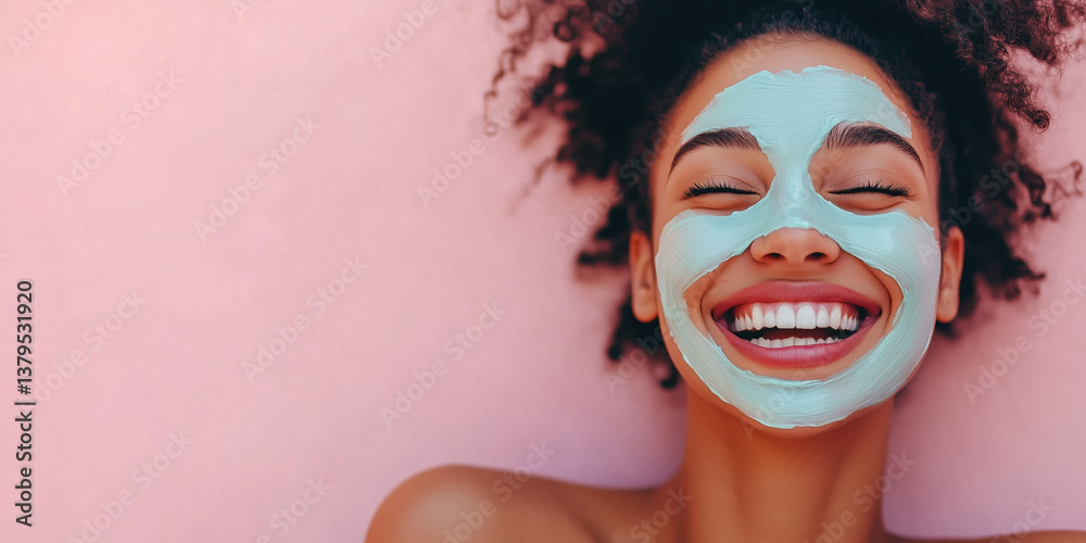 Close-up of a smiling young woman with a face mask on a pink background.