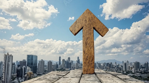 large wooden arrow points upward against cityscape backdrop, symbolizing progress and growth under partly cloudy sky. urban skyline stretches into distance