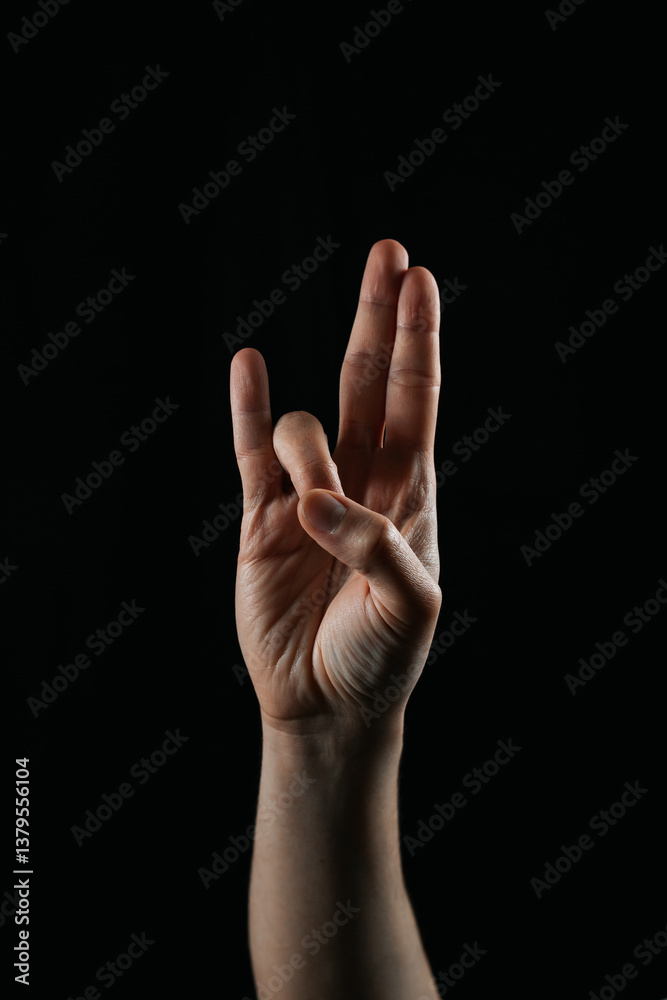 Close-up of a hand making a unique finger gesture on a black background. Symbolic or expressive sign, ideal for communication, creativity, or cultural context concepts. Close-up of a hand making a unique finger gesture on a black background. Symbolic or expressive sign, ideal for communication, creativity, or cultural context concepts.