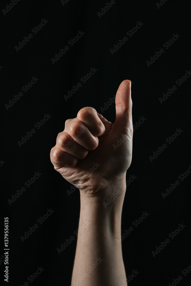 Close-up of a hand showing thumbs up gesture on black background. Symbol of approval, success, agreement, and positivity. Simple and powerful non-verbal communication. Close-up of a hand showing thumbs up gesture on black background. Symbol of approval, success, agreement, and positivity. Simple and powerful non-verbal communication.