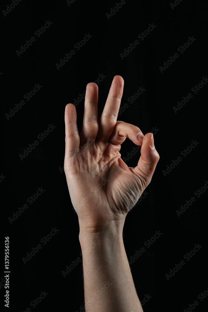 Hand showing OK gesture on black background. Symbol of approval, agreement, satisfaction, and positivity. Simple and powerful body language. Hand showing OK gesture on black background. Symbol of approval, agreement, satisfaction, and positivity. Simple and powerful body language.
