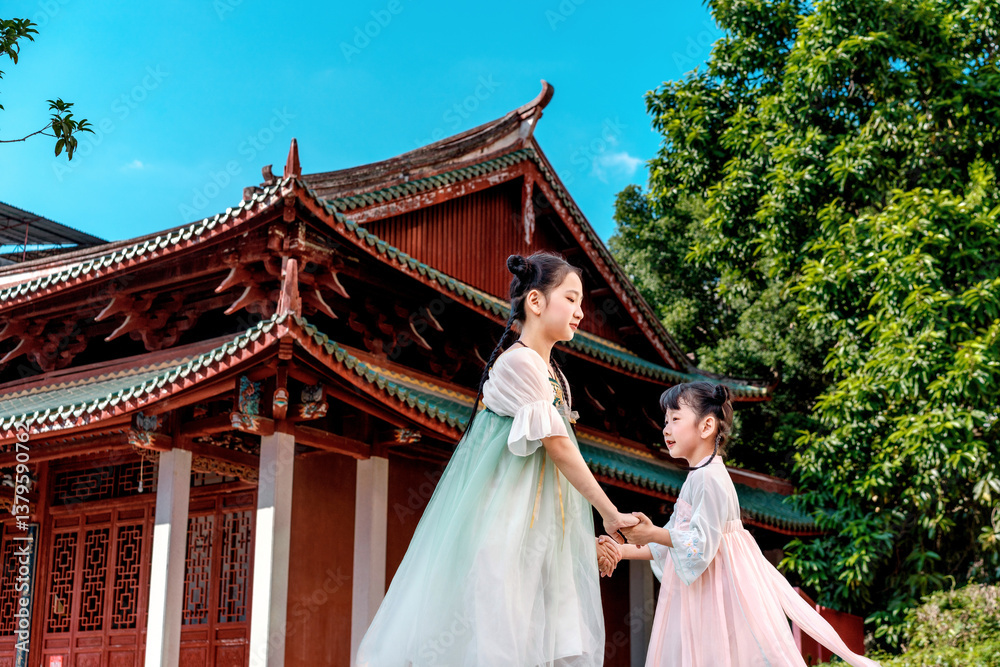 Fototapeta premium Cute Hanfu sisters playing outside the ancient building