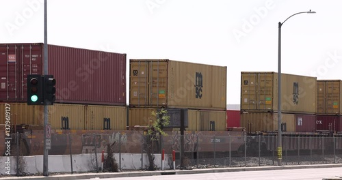 Compton, California, USA - April 2, 2025: An intermodal stack freight train loaded with containers passes towards the port of Los Angeles.