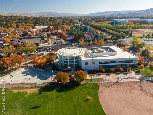 Aerial view of San Ramon City Hall, San Ramon, California, USA during autumn. The photo captures the colorful foliage, a modern building, and a baseball field.