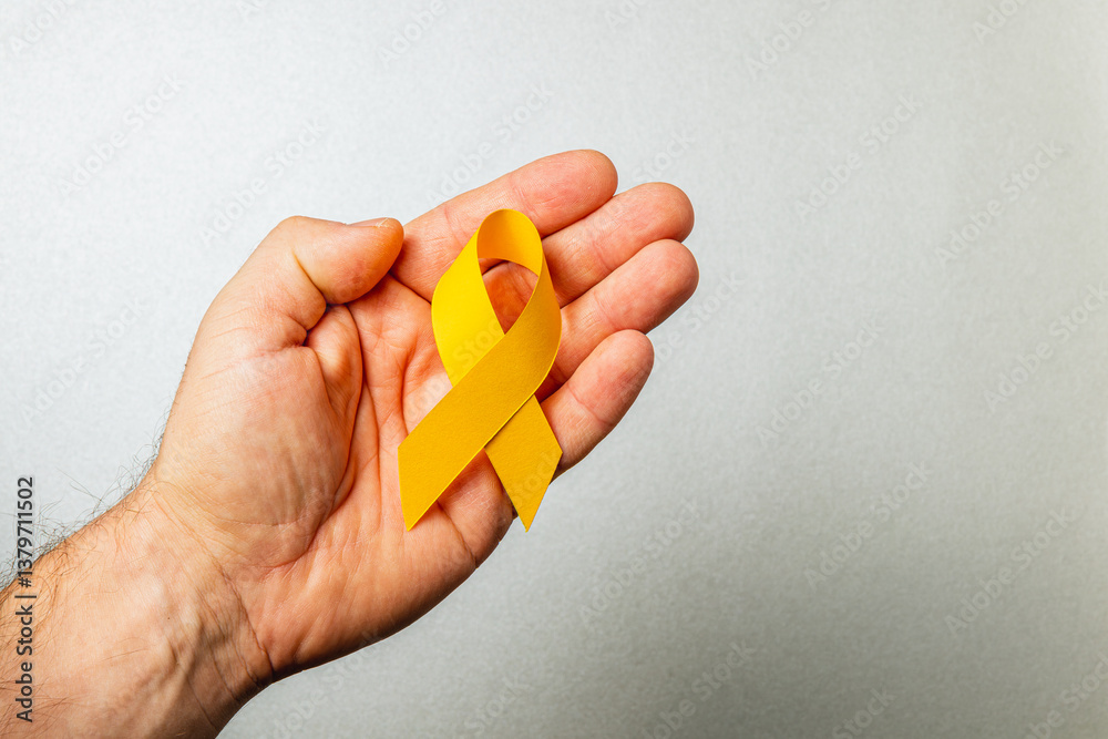 Hold a yellow ribbon symbolizing hope in the fight against cancer Hold a yellow ribbon symbolizing hope in the fight against cancer