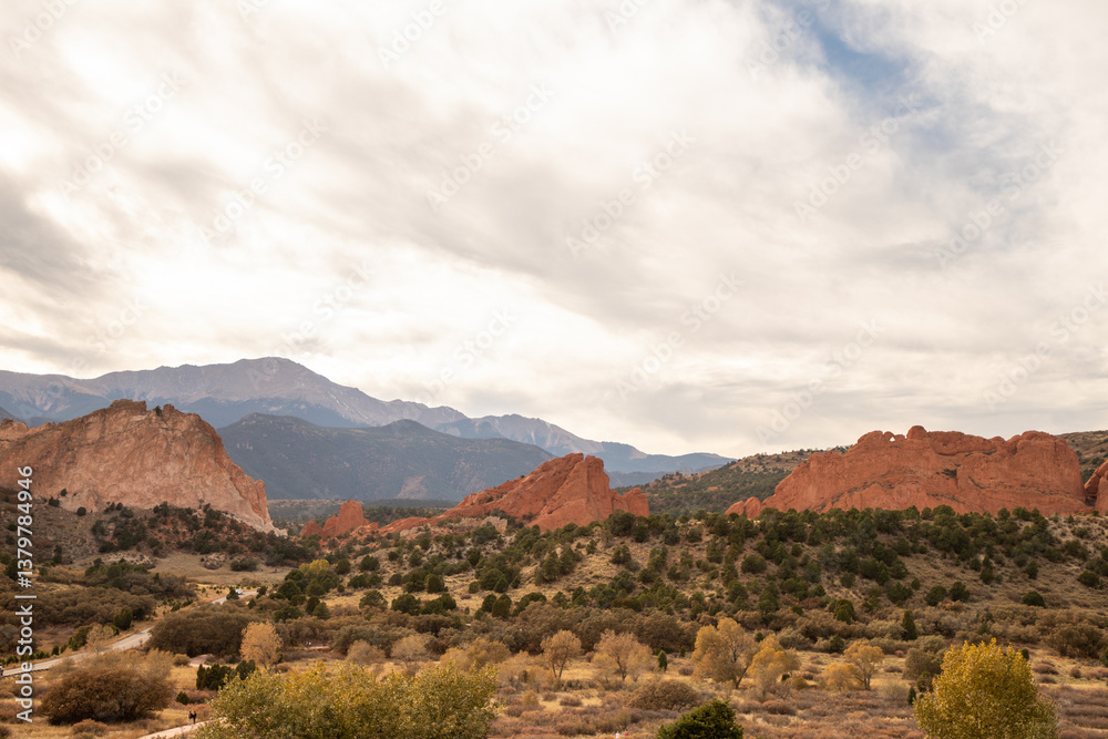 Fototapeta premium Garden of the Gods rock formations glow under afternoon sun with sparse trees and desert terrain