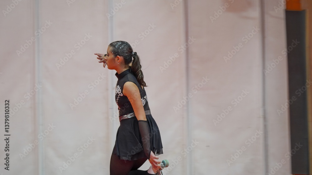 Young woman competing in a roller skating championship wearing a black and silver costume