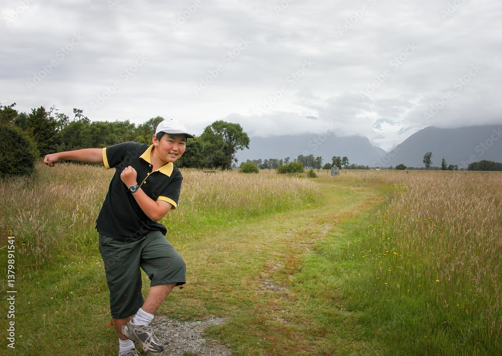 Boy posing for fun photos. Fox Glacier in the cloud. South Island. New Zealand.