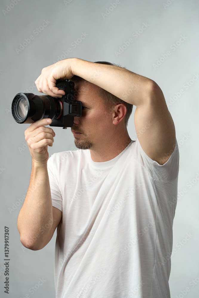 Photographer in Action. A man in a white t-shirt takes a photo with a camera Photographer in Action. A man in a white t-shirt takes a photo with a camera