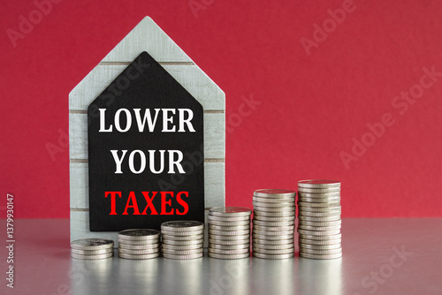 Obraz na płótnie Lower your taxes symbol. Concept words Lower your taxes written on a black board. Silver coins arranged in a graph in front. Beautiful red background, grey table. Business concept. w salonie