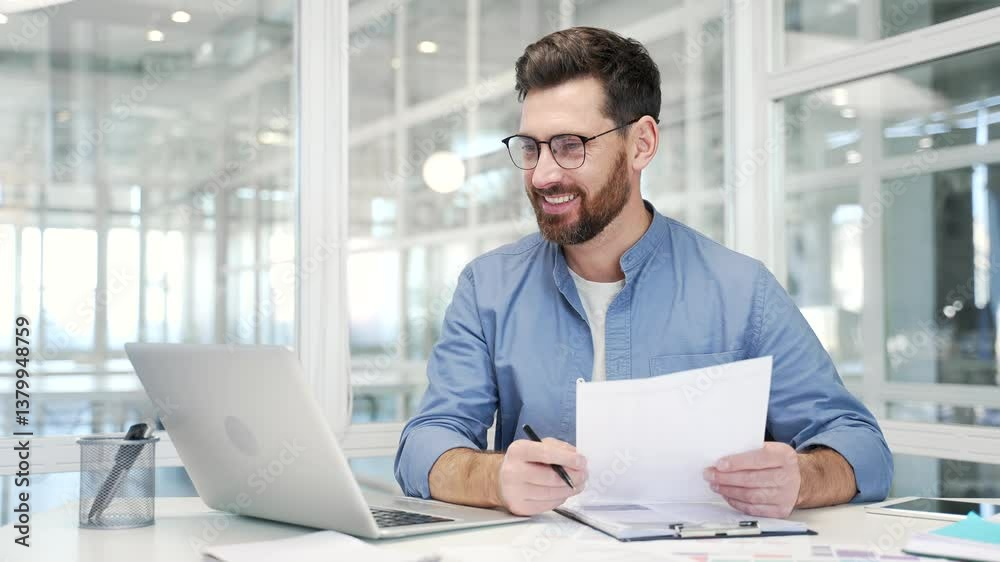 Joyful businessman is satisfied with the results of a financial report holding documents in his hands sitting at workplace in a business office. Entrepreneur or owner is happy with positive indicators Joyful businessman is satisfied with the results of a financial report holding documents in his hands sitting at workplace in a business office. Entrepreneur or owner is happy with positive indicators