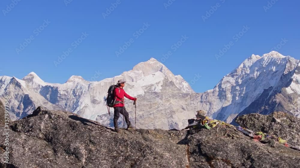 Aerial view of a mountaineer standing on a rocky summit in Nepal, enjoying the breathtaking panorama of the Himalayas and Mount Everest Aerial view of a mountaineer standing on a rocky summit in Nepal, enjoying the breathtaking panorama of the Himalayas and Mount Everest