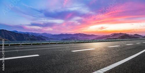 Obraz na płótnie Empty asphalt highway leads towards stunning mountain range at colorful sunset w salonie