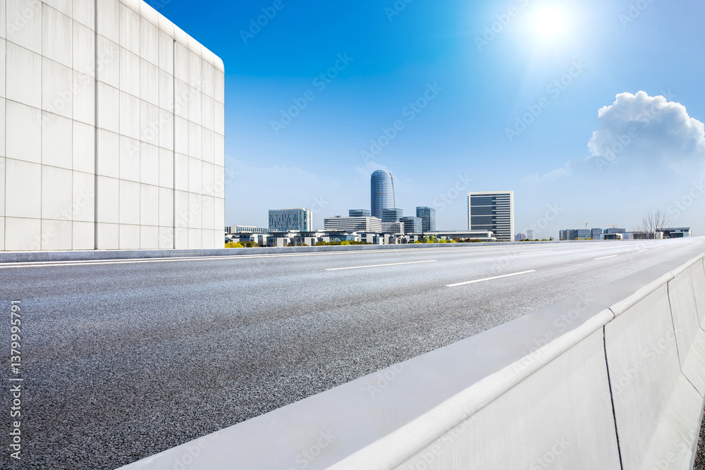 Empty asphalt road and city skyline with modern buildings scenery under a sunny blue sky