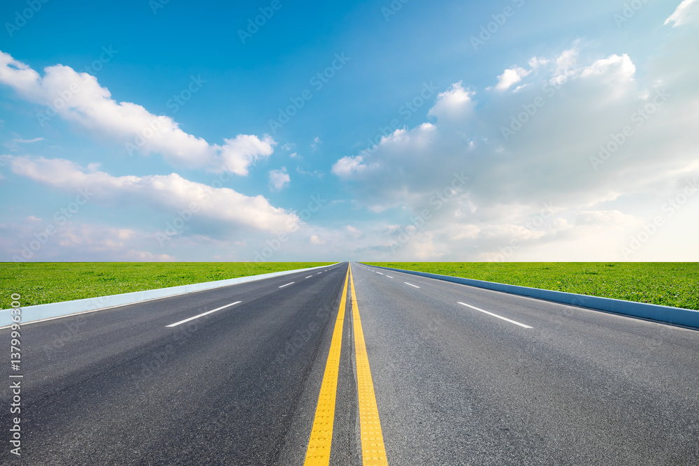 Asphalt highway stretches through green grass fields on a sunny day