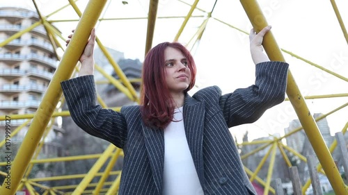 Beautiful girl with red hair posing on yellow background. Woman in jacket posing. Woman in business suit smiling. Red-haired girl with beautiful smile posing.