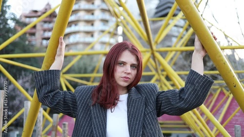 Beautiful girl with red hair posing on yellow background. Woman in jacket posing. Woman in business suit smiling. Red-haired girl with beautiful smile posing.