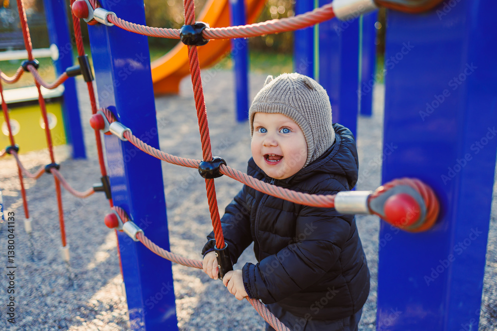 Obraz premium A joyous child is gleefully playing on a colorful and vibrant climbing structure at a playground, basking in the warm sunlight of autumn, embodying the essence of happiness and innocence