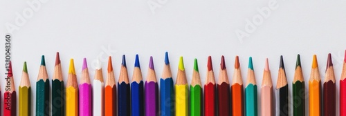 Vibrant array of colored pencils and paint brushes along white workspace for creative projects and artistic expression