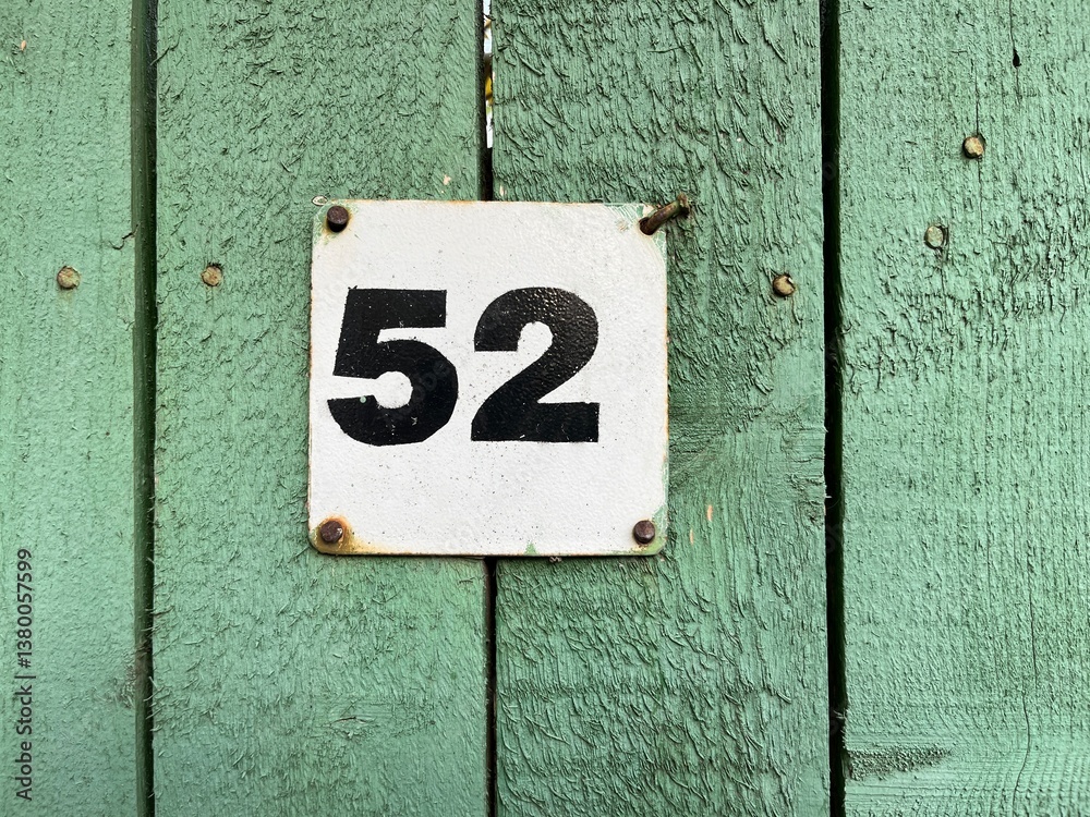 Number 52 Sign on a Green Wooden Fence in Daylight Number 52 Sign on a Green Wooden Fence in Daylight
