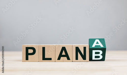 Rows of wooden cubes change from Plan A to Plan B on a wooden table. Concept of planning, contingency plans and risk management with backup plans.