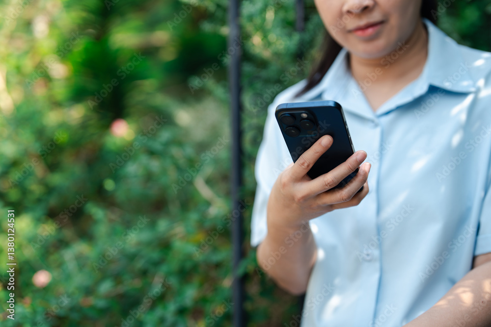Woman in casual attire using smartphone outdoors. Close-up digital lifestyle communication and mobile technology concept. Social media interaction, connectivity in natural garden background. Woman in casual attire using smartphone outdoors. Close-up digital lifestyle communication and mobile technology concept. Social media interaction, connectivity in natural garden background.