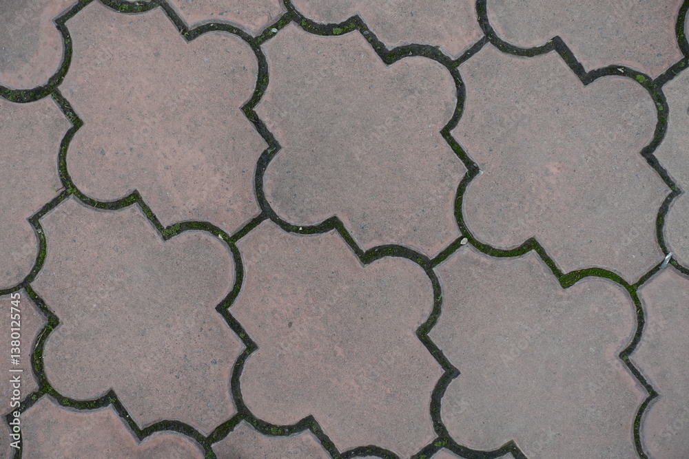 Closeup of pale pink pavement of interlocking concrete tiles with moroccan lattice layout