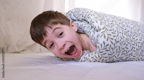 The child was rolled up in a blanket and his feet are tickling. Wrapped boy needs help he is ticklish. Bad joke and game. Psychological problems. Physical touch against will. Unpleasant sensations. 4K