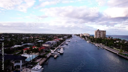 Boca Raton, Florida aerial jib up of intracoastal waterway. Boats, yachts, and luxury homes line the waterway up to the horizon. The Atlantic Ocean is visible to the right.