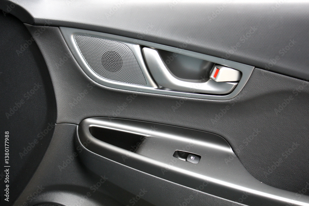 Door handle with music speaker of a modern electric car. Black interior of the luxury modern car. Passenger door trim. Door handle with music speaker of a modern electric car. Black interior of the luxury modern car. Passenger door trim.