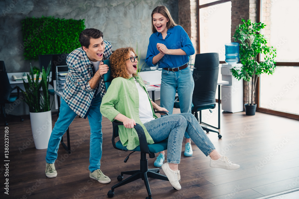 Fototapeta premium Diverse group of colleagues enjoying a fun team-building activity with office chairs, showcasing teamwork, collaboration
