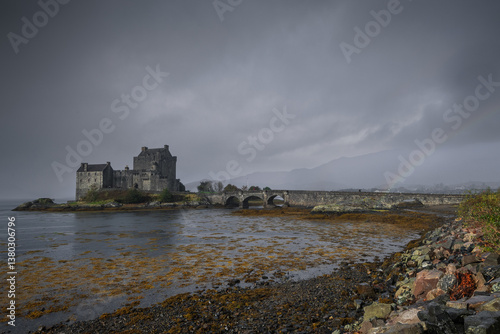 Obraz na płótnie Eilean Donan Castle stands majestically amid autumn hues, its reflection shimmering in calm waters. Misty Highlands and golden trees create a scene of timeless beauty. w salonie