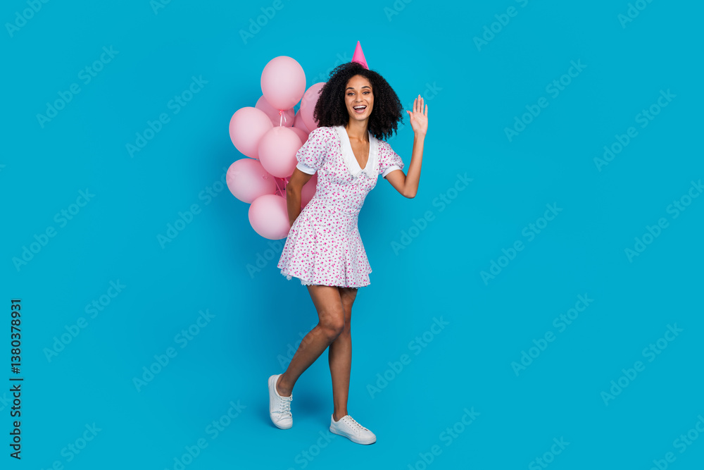 Cheerful young woman enjoying party in stylish dress with pink balloons and blue background, expressing joy and fun Cheerful young woman enjoying party in stylish dress with pink balloons and blue background, expressing joy and fun