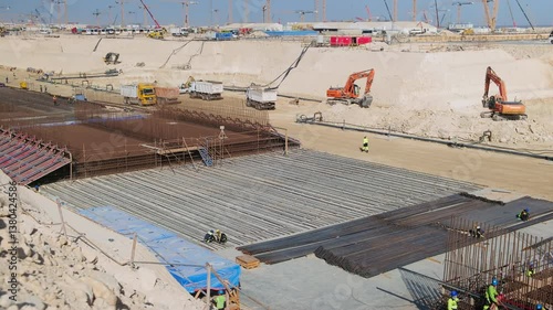 Reinforced concrete foundation of tunnel under construction in open foundation pit. Trucks and machineries at background. Working progress at construction site